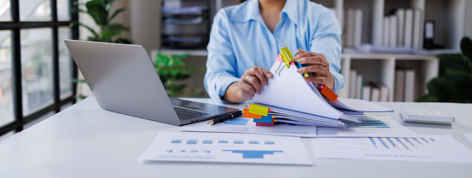 Businesswoman hands working in Stacks of paper files for searching and checking unfinished document achieves on folders papers at busy work desk office

