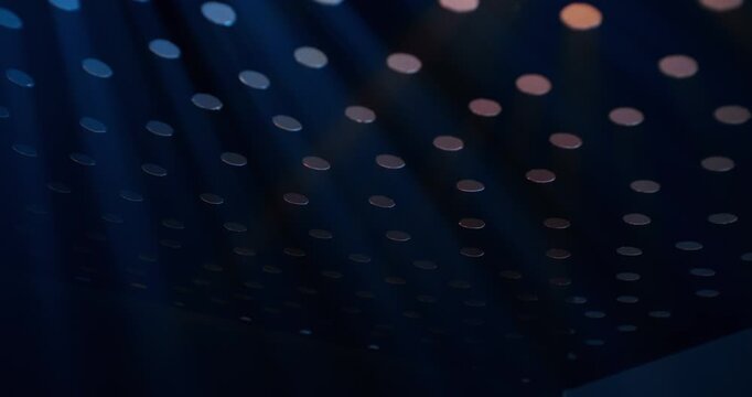 Beams of light through small round holes on a black surface