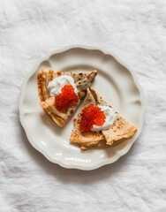 Crepes with greek yogurt and red caviar - russian breakfast on a light background, top view