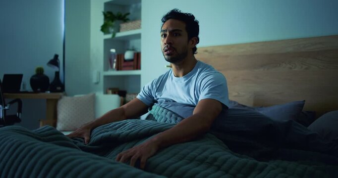 Scared, man and nightmare in bedroom at night from psychosis, ptsd flashback and panic attack. Shocked, male person or fear reaction of bad dream, emotional trauma and terror of hallucination in home