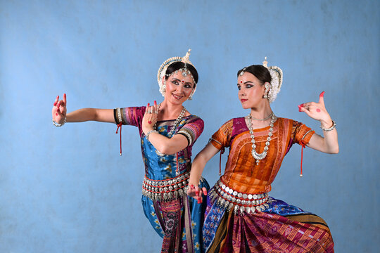 Indian female dancers in beautiful costumes on a blue background in the studio in dance poses