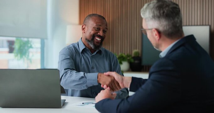 Businessmen, meeting and handshake with laptop for corporate proposal or negotiation. Mature, business people or employees shaking hands with smile for partnership, b2b or onboarding in workplace