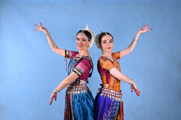 Indian female dancers in beautiful costumes on a blue background in the studio in dance poses
