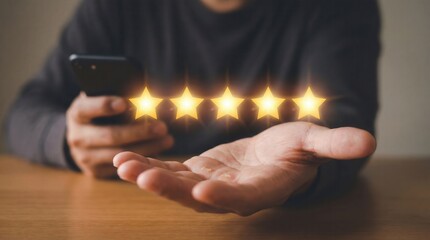 A person holds a dark smartphone while an open palm displays five glowing golden stars above a wooden table symbolizing excellent customer satisfaction and top service