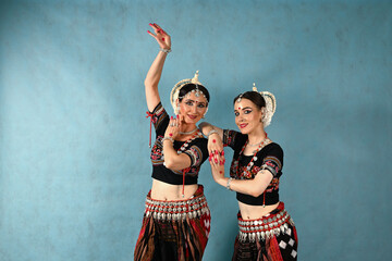 Indian female dancers in beautiful costumes on a blue background in the studio in dance poses