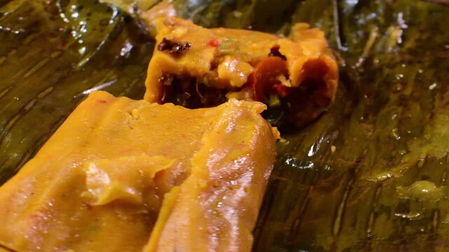 Opened hallaca with vibrant fillings on banana leaves, evokes traditional warmth