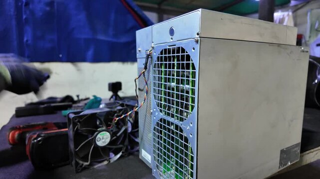 Worker using cordless drill to assemble a crypto mining machine rig