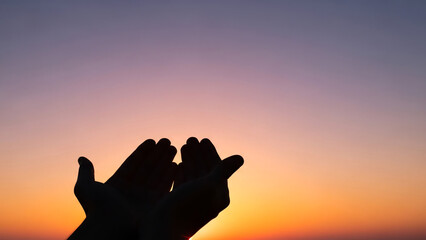 Soulful prayer hands silhouette with sunset sky and copy space for Ramadan
