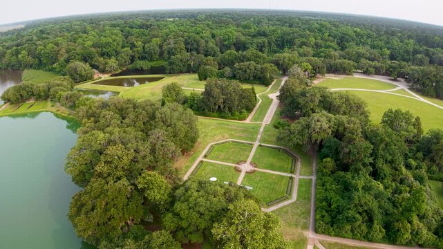 Aerial drone footage glides over formal geometric gardens and reflecting pools at Middleton Place Plantation in Charleston South Carolina showing intersecting paths green lawns and surrounding trees.