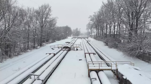 Oil pipeline scene showcasing extensive network of pipes on snowy landscape at cold winter. Aerial shot revealing infrastructure and natural surroundings emphasizing energy transport. Industrial pipes