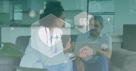 Animation of medical icons over diverse female doctor and male patient using tablet in hospital - Powered by Adobe