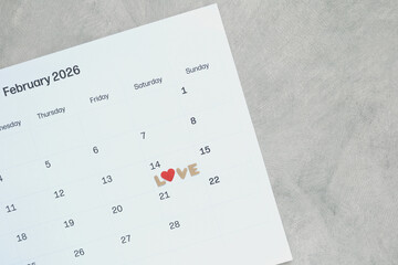 Valentine's Day reminder with a red heart and LOVE letters on a February calendar page. Romantic date planning, wedding anniversary, love concept, and seasonal holiday marketing content. Top view.