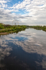 Ferris wheel and river landscape with sky reflection