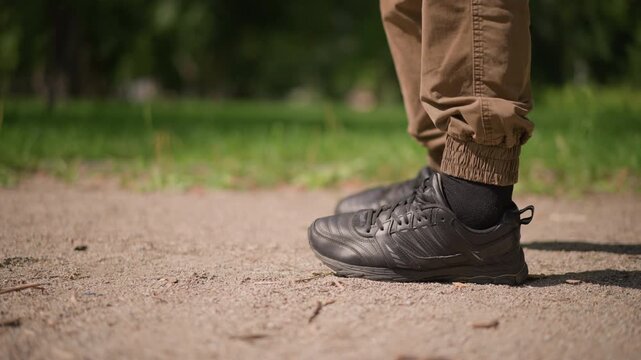 Sneakers With Deliberate Steps, Close View Of Sports Shoes On Sandy Ground Showing Precise Foot Positioning, Detailed Image Of Athletic Footwear And Foot Movement On Gravelly Outdoor Surface