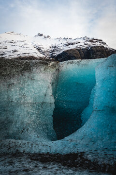 View of the frozen sapphire ice cave, a glacial cavern glowing with ethereal blue light beneath a snow-capped mountain, Vatnajokull glacier, Iceland.