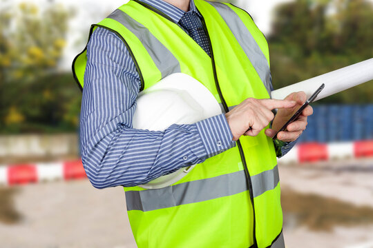 Engineer with blueprints using smartphone on site - Powered by Adobe