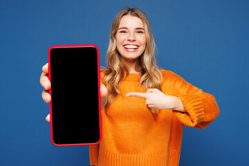 Young happy woman wears yellow sweater casual clothes hold in hand use point finger on mobile cell...