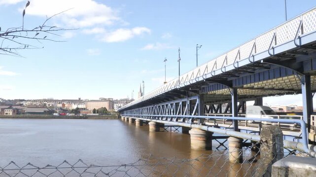 Craigavon Bridge lower deck south facing from Waterside to Cityside in Derry Londonderry on a bright day with blue sky with vehicles passing. 