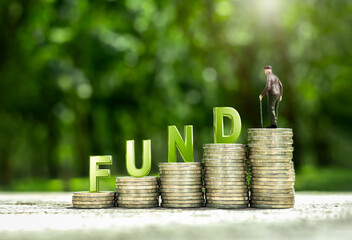 Elderly male doll on pile of coins money with word FUND. Concept of financial planning, investing in Retirement Mutual Funds (RMF), dividends, and financial risk management.