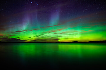 Northern lights dancing over calm lake in north of Sweden.