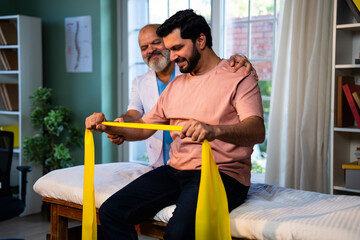 Indian physiotherapist teaching patient resistance band exercises for shoulder strength training