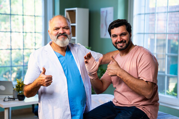 Indian physiotherapist treating wrist pain by applying support band to male patient