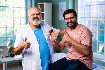 Indian physiotherapist treating wrist pain by applying support band to male patient
