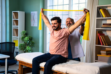 Indian physiotherapist teaching patient resistance band exercises for shoulder strength training