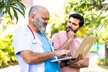 Indian doctor patient discuss case outdoors while reviewing medical details in nature