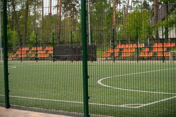 Fototapeta premium football field with white lines on the grass. With orange stands.