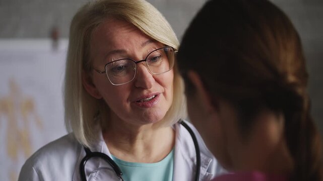 Senior woman doctor talking to female patient and sharing positive check-up news