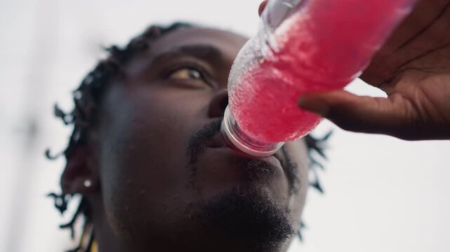 Outdoor athlete pauses to hydrate intensely, Focused runner pauses to drink during intense outdoor workout session, Closeup of determined athlete rehydrating during tough outdoor training session