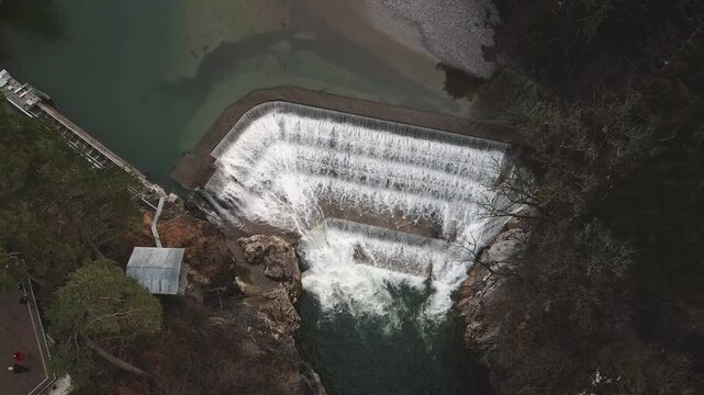 Slow motion drone descends to Lechfall dam in Fussen, highlighting frothy whitewater spill, turquoise reservoir and rocky gorge in fall light. Cinematic Bavarian falls.