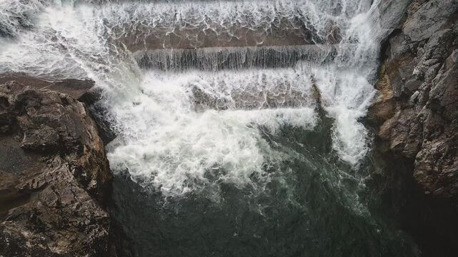 Slow motion drone pans up Lechfall's dramatic tiered dam in Fussen, emphasizing roaring multi-level cascade, foam and rocky drop into turquoise gorge. Hypnotic Bavarian hydro.