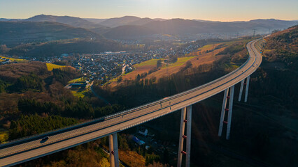 Obraz premium Stunning sunset panorama over the Ruhr valley featuring the Talbrücke Nuttlar. Epic aerial landscape for travel, industry, and engineering concepts.