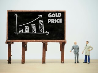 Mini toy of action figure at table with blurred background. Business financial photography concept design. Minifigure of businessman character with GOLD PRICE graph at blackboard. Increase arrow chart