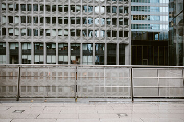 Urban architecture modern corporate facade, grid pattern and fence framing an empty plaza perspective with clean geometry in city district