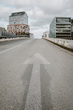 Urban architecture modern road with arrow on asphalt, direction toward skyline, empty perspective and clean leading lines for travel concept