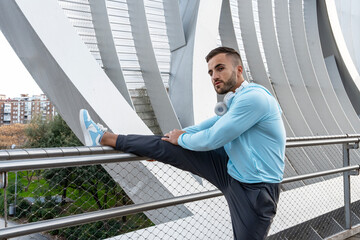 Fitness enthusiast stretching on a modern bridge in the city during the early morning light