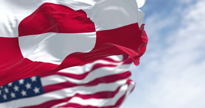 Flags of Greenland and the US waving in the wind on a clear day
