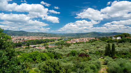 View of houses, hills, and forests around Florence, Italy, on a sunny day with a clear blue sky, capturing the serene Tuscan landscape and traditional countryside charm.
