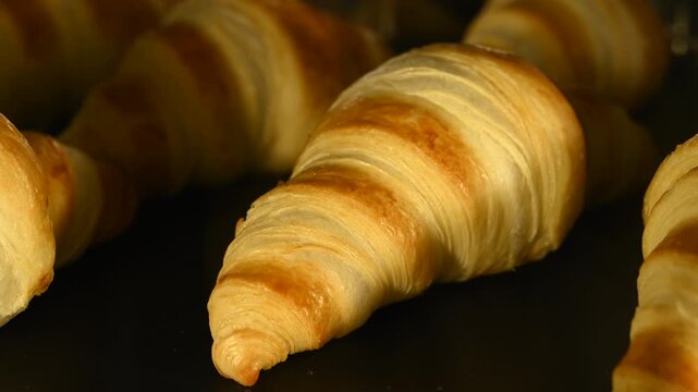 Timelapse video of homemade croissants baking inside an oven, gradually rising and turning golden brown. The footage captures the transformation of raw dough into flaky, freshly baked pastries