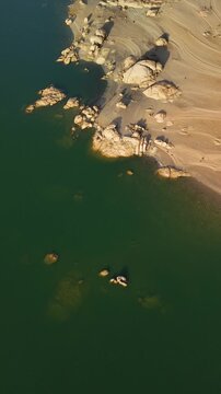 Overhead view of green lake water and rocky shoreline, Almendra Reservoir, Spain
