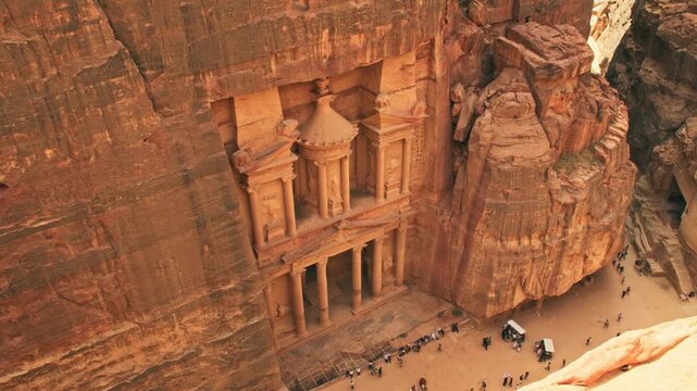 View from above Al-Khazneh Treasury in Petra, Jordan, showing tourists at the base of the carved sandstone facade in the ancient Nabataean city