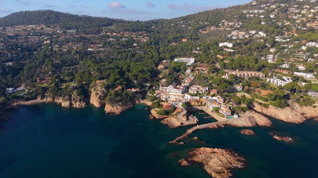 Aerial view moving forward above the picturesque fornells town and aiguablava bay on the costa brava, showcasing the rugged coastline, turquoise sea, and pine forests in catalonia, spain