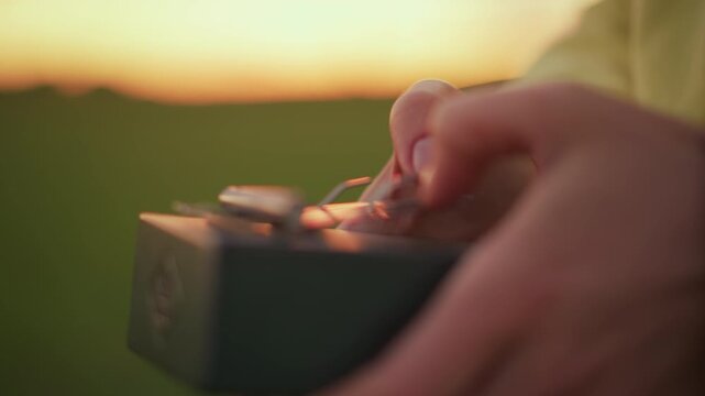 hands plucking kalimba at golden hour, white busker improvises lively thumb piano melody in open field with warm sunset glow and soft bokeh, closeup of thumbs and levers showing tactile rhythm