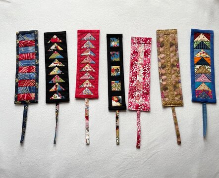 Handmade fabric bookmark featuring intricate foundation paper piecing (FPP) Flying Geese pattern, crafted from colorful patchwork triangles in Japanese, floral, and geometric prints.