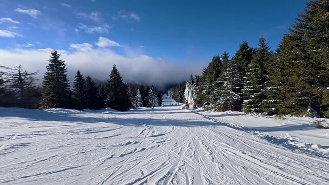 Beautiful POV ski landscape on the mountains. Skier skis down a snowy mountain trail in sunny weather.