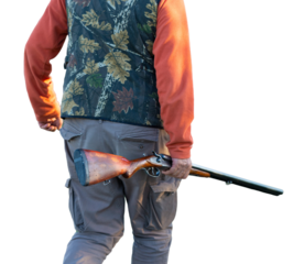 Mature hunter man holding a shotgun and walking through a field