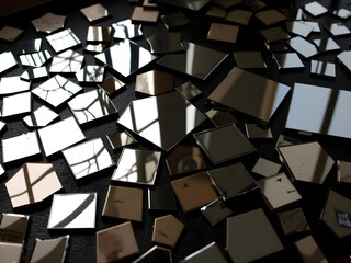 A large collection of mirrors are scattered across a black background